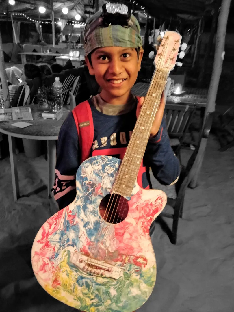 This is Nilay. 

With a fancy guitar. And a headband. A headlight. Layered T shirts. A bright backpack. And a grin.